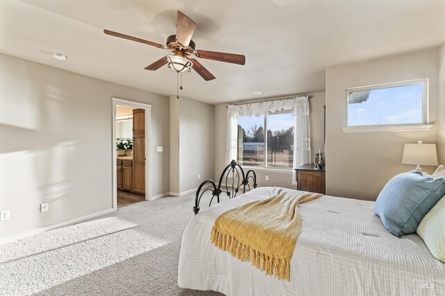 carpeted bedroom with baseboards, connected bathroom, and a ceiling fan