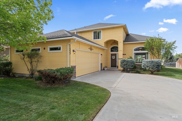 view of front facade with concrete driveway, a front yard, an attached garage, and a shingled roof