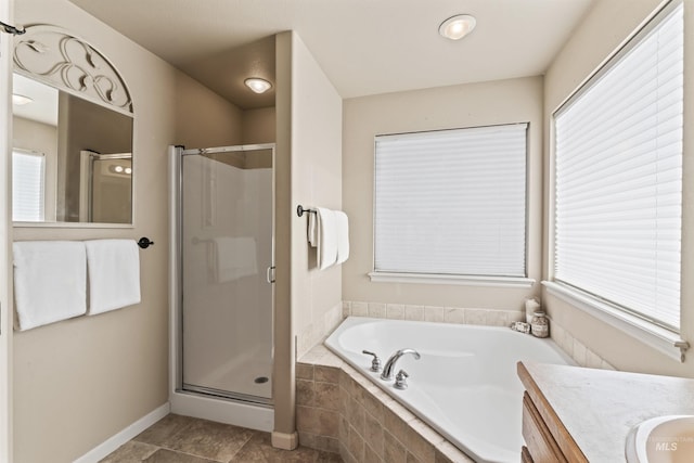 bathroom with vanity, a bath, a shower stall, and healthy amount of natural light