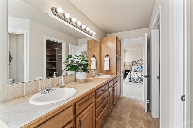 bathroom with double vanity, connected bathroom, and toilet