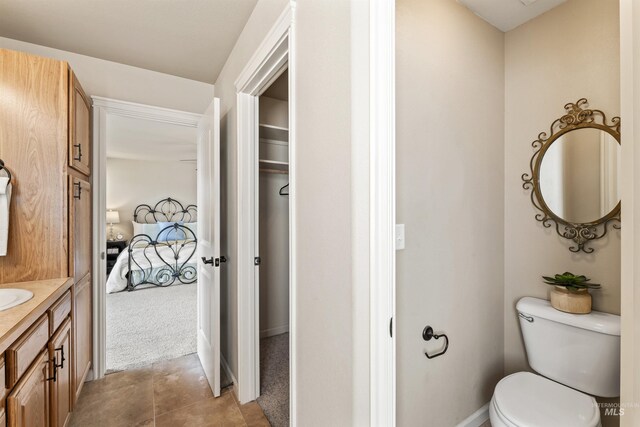 ensuite bathroom featuring toilet, vanity, baseboards, and tile patterned floors
