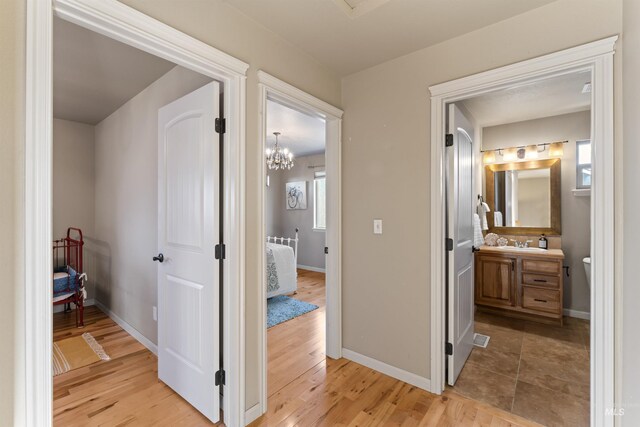 hall featuring light wood finished floors, a sink, and baseboards