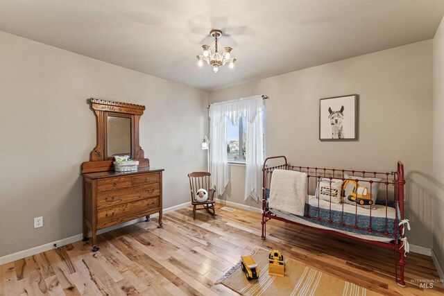 bedroom with a chandelier, wood finished floors, and baseboards