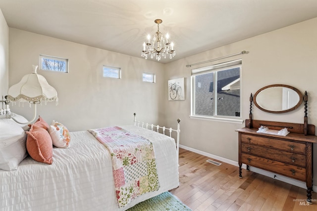 bedroom featuring wood-type flooring, multiple windows, a chandelier, and baseboards