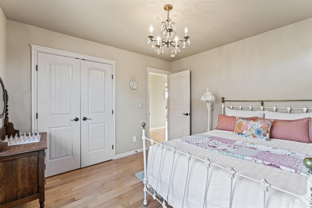 bedroom with a chandelier, light wood-style flooring, a closet, and baseboards