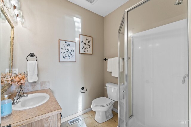 bathroom with toilet, tile patterned flooring, a shower stall, vanity, and baseboards