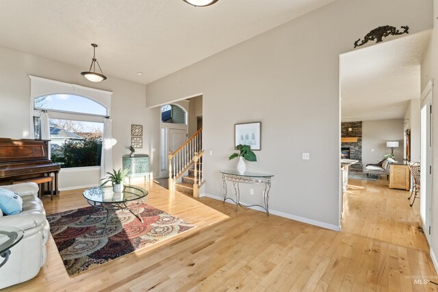 living area with stairway, light wood-type flooring, a fireplace, and baseboards
