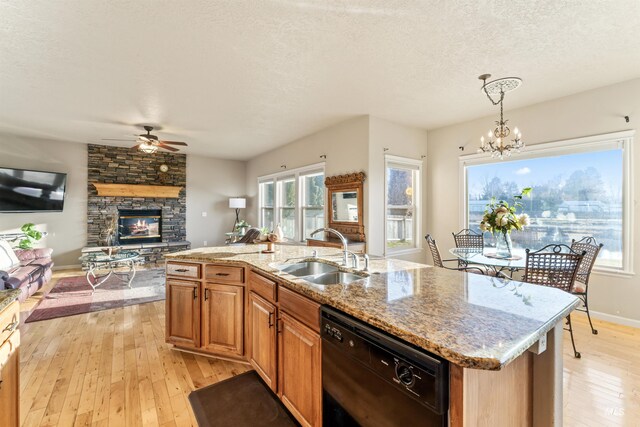 kitchen featuring a sink, dishwasher, light wood-type flooring, a ceiling fan, and a textured ceiling
