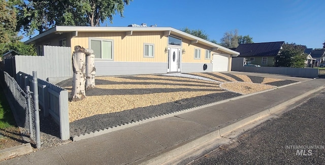 view of front facade with a garage, driveway, and fence