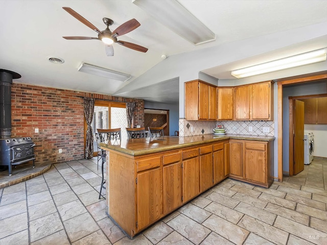 1872 E 1750 S, Gooding, ID 83330 - kitchen featuring a ceiling fan, vaulted ceiling, a wood stove, stone tile floors, and decorative backsplash