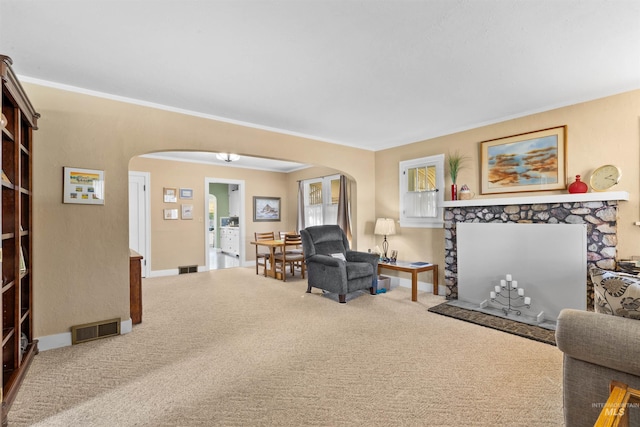 carpeted living room featuring visible vents, a fireplace, and arched walkways