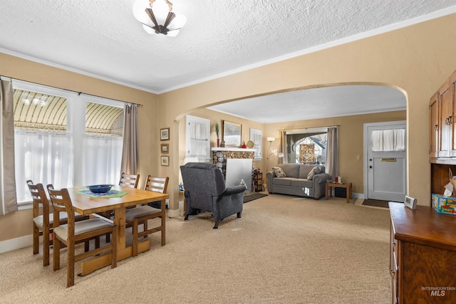 dining space featuring light carpet, baseboards, arched walkways, and crown molding