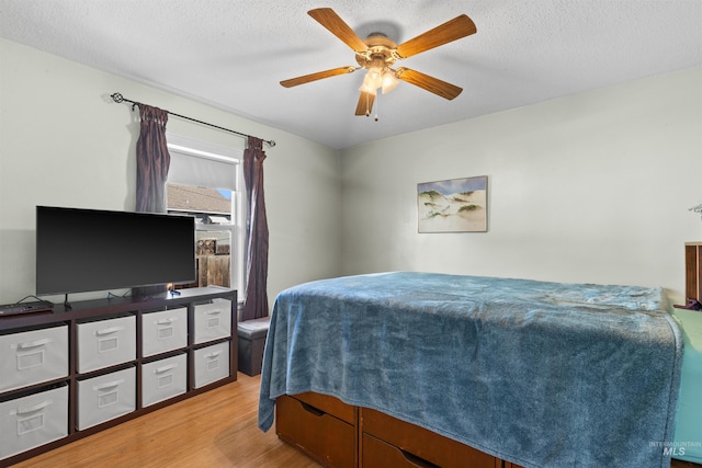 bedroom with ceiling fan, a textured ceiling, and wood finished floors