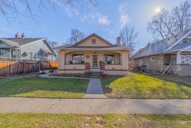 bungalow with a porch, a front lawn, fence, and stucco siding