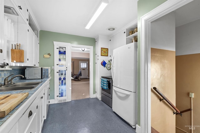 kitchen with dark floors, freestanding refrigerator, stainless steel electric range, white cabinetry, and a sink