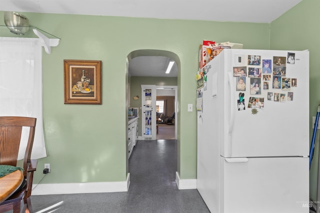 hall featuring baseboards and arched walkways