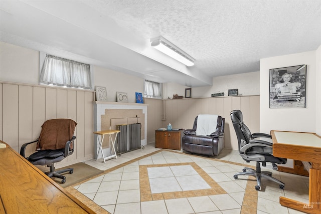 office space with a textured ceiling, a wainscoted wall, and tile patterned floors