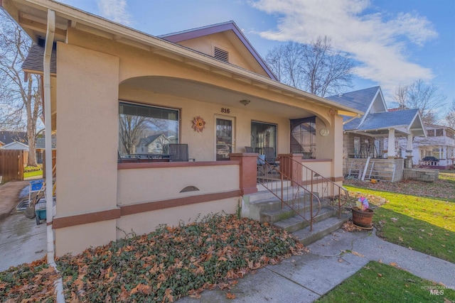 view of front of property with a porch, fence, and stucco siding