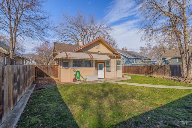 back of property featuring a lawn, a chimney, a fenced backyard, and stucco siding