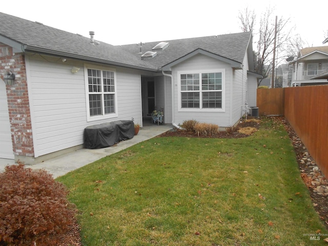 rear view of house featuring a lawn and central AC