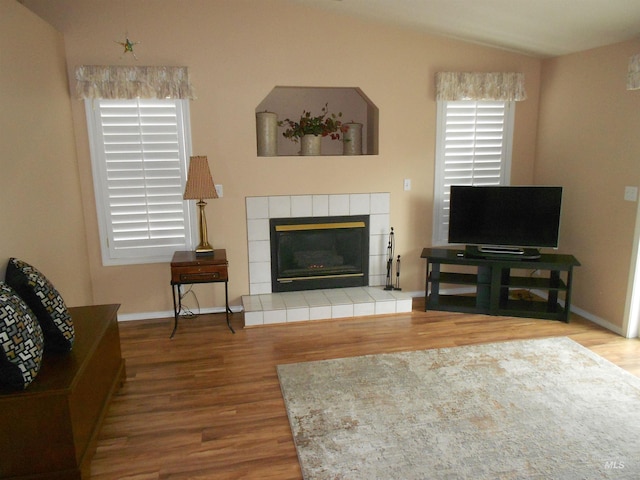 living room with lofted ceiling, hardwood / wood-style flooring, and a tile fireplace