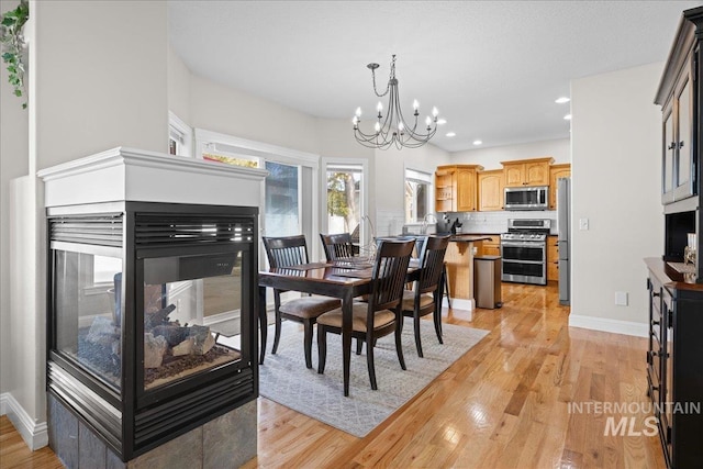 605 W Highland Ave, Nampa, ID 83686 - dining area with baseboards, light wood-type flooring, recessed lighting, a multi sided fireplace, and a notable chandelier