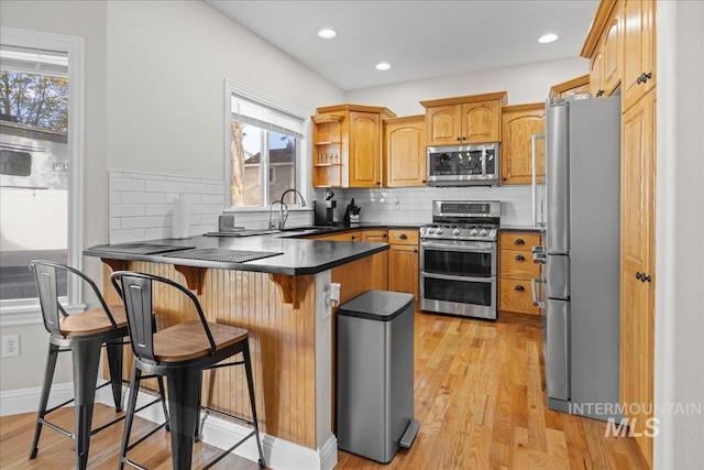 605 W Highland Ave, Nampa, ID 83686 - kitchen with decorative backsplash, a peninsula, dark countertops, a sink, and appliances with stainless steel finishes