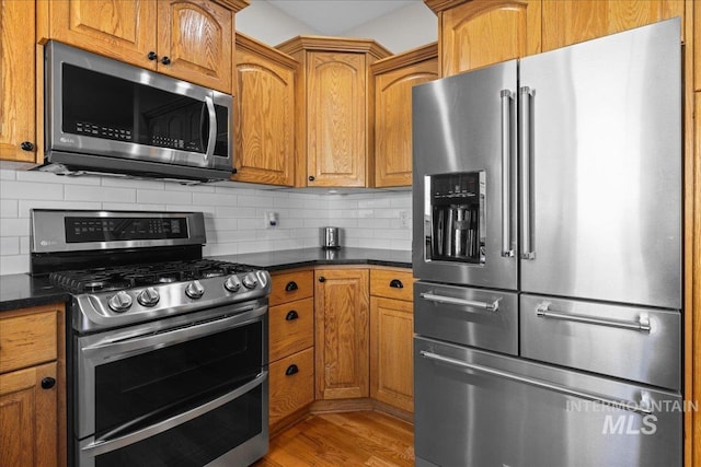 605 W Highland Ave, Nampa, ID 83686 - kitchen featuring brown cabinetry, light wood-style flooring, backsplash, and stainless steel appliances