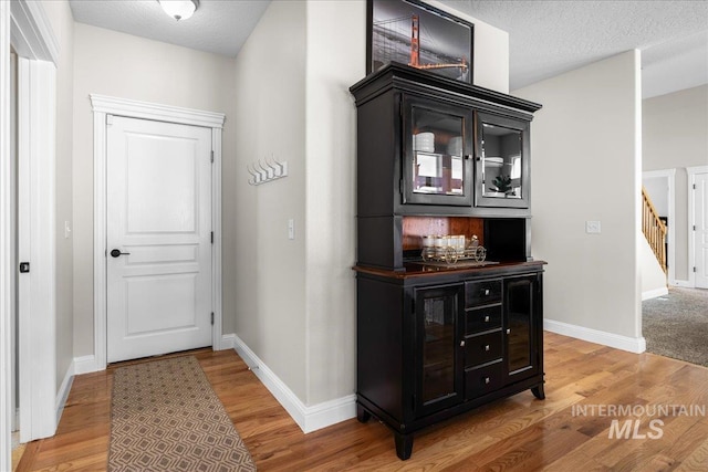 605 W Highland Ave, Nampa, ID 83686 - corridor featuring stairs, a textured ceiling, baseboards, and light wood-style floors