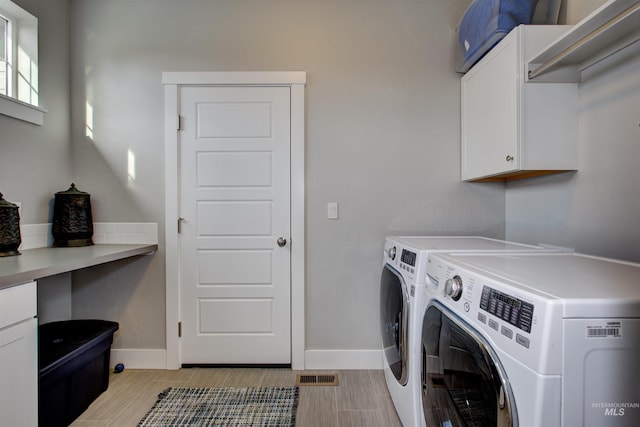 washroom with cabinets and washing machine and dryer