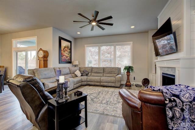 living room featuring ceiling fan, light hardwood / wood-style floors, a wealth of natural light, and a tiled fireplace