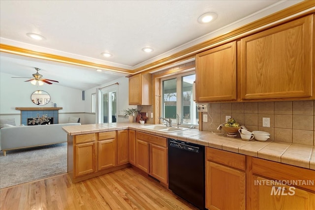 kitchen with light wood-style flooring, a fireplace, a sink, black dishwasher, and open floor plan