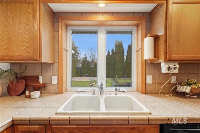 kitchen with brown cabinetry, a wealth of natural light, a sink, and decorative backsplash