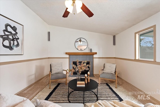 sitting room with a textured ceiling, carpet floors, a fireplace, and a ceiling fan