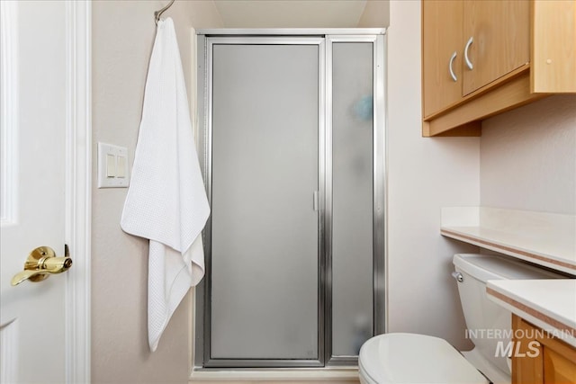 full bath with vanity, a shower stall, and toilet