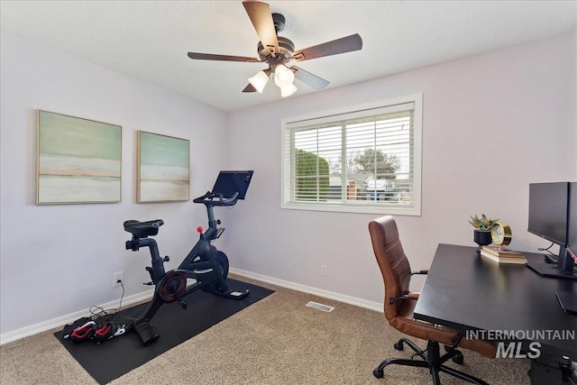 carpeted office space with ceiling fan, visible vents, and baseboards