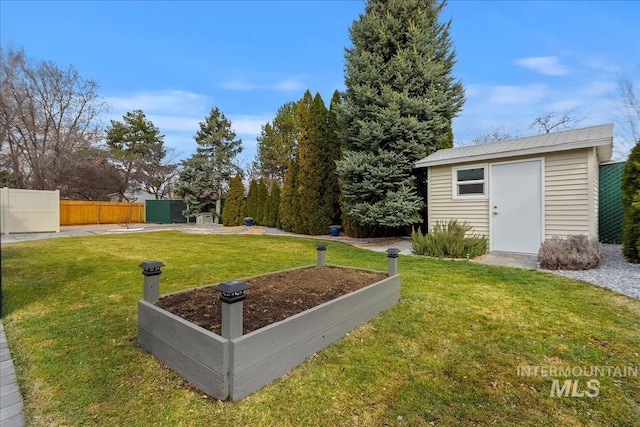 view of yard with a garden, fence, and an outbuilding