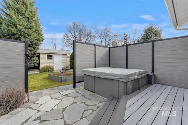 wooden deck with an outbuilding, a shed, a covered hot tub, and fence