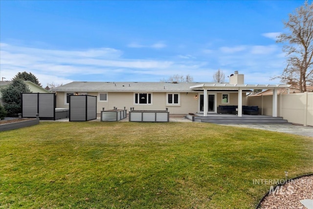 rear view of property featuring a yard, fence, a chimney, and an outdoor hangout area