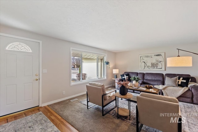 living room with wood finished floors, visible vents, and baseboards