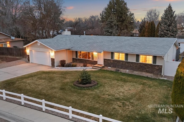 ranch-style home featuring a fenced front yard, concrete driveway, stone siding, and a garage