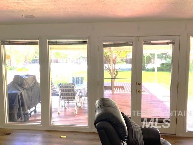 doorway to outside featuring plenty of natural light, wood finished floors, a textured ceiling, and french doors