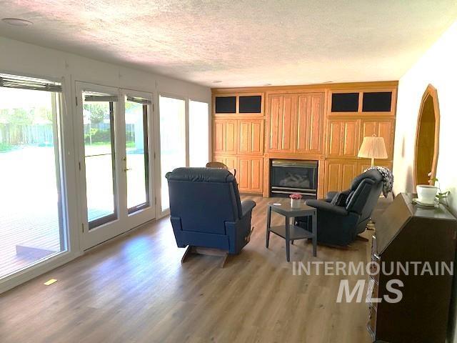living room featuring light wood-style floors, a textured ceiling, and a glass covered fireplace