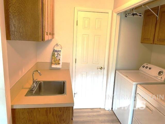 laundry room with separate washer and dryer, cabinet space, and light wood finished floors