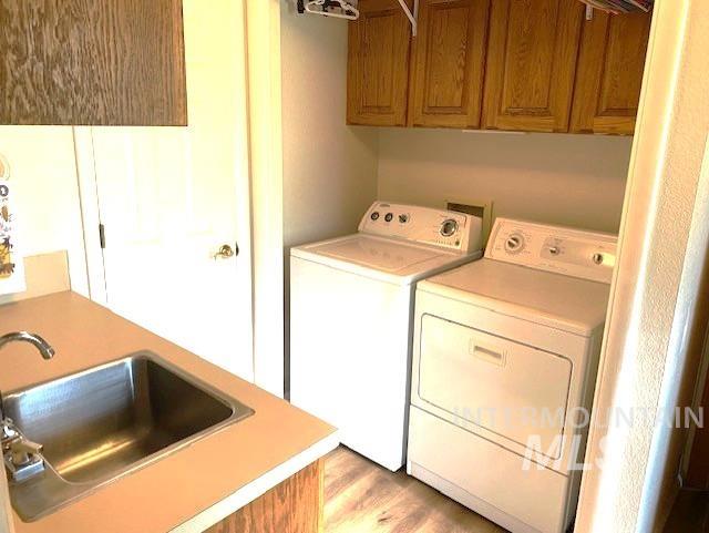 laundry area with washer and dryer, cabinet space, and light wood-style floors