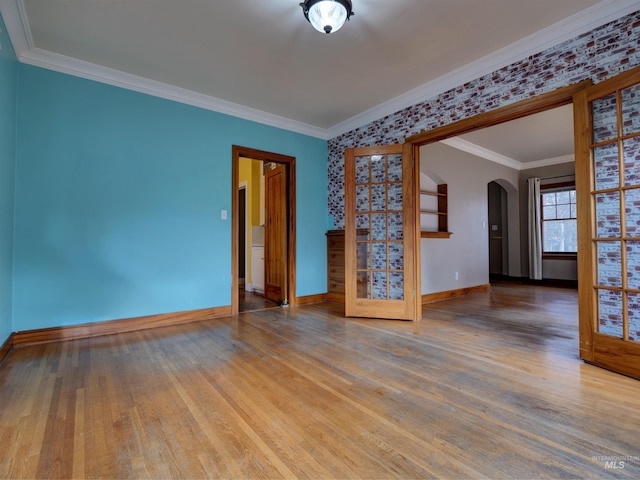 spare room with crown molding, brick wall, wood-type flooring, and french doors