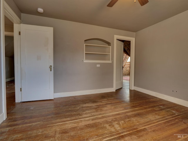 spare room with ceiling fan, dark hardwood / wood-style flooring, and built in features