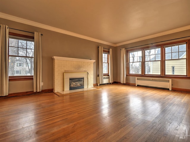 unfurnished living room featuring radiator, a fireplace, ornamental molding, and wood-type flooring