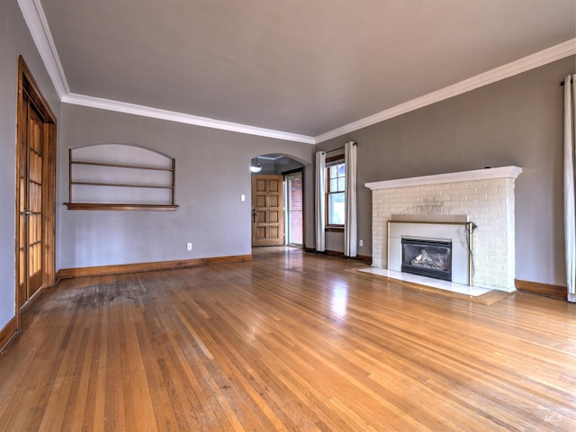 unfurnished living room with crown molding, a fireplace, and hardwood / wood-style flooring