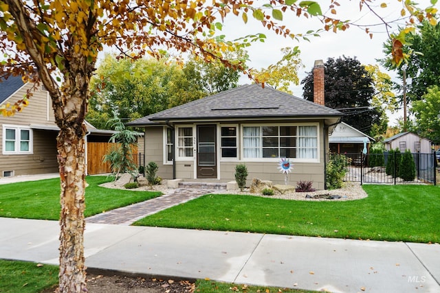 bungalow-style home featuring a front yard, fence, and roof with shingles